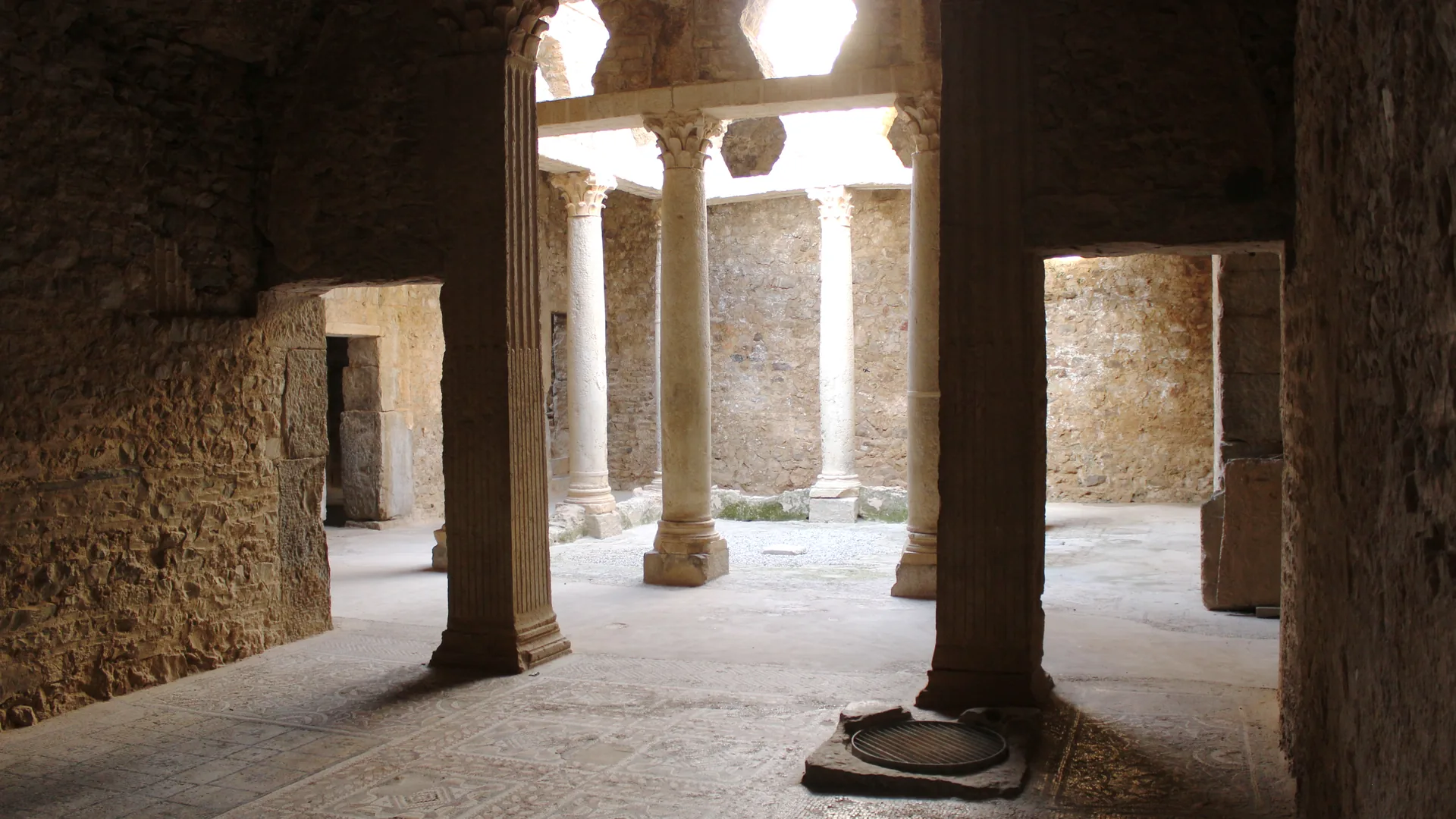 The columned underground peristyle courtyard and mosaic floor of a Roman villa at Bulla Regia, Tunisia